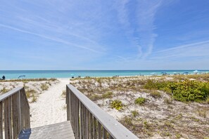 A beach pathway leading to the ocean with a wooden boardwalk.