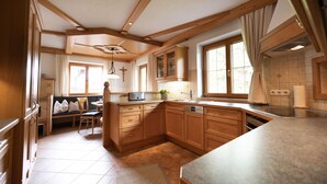 A kitchen with wooden cabinets, a built-in oven, and a large window. - Spacious vacation apartment in Kaiserwinkl - perfect for the whole family (Kössen)