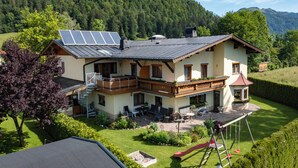 A two-story house with a balcony, solar panels, and a garden. - Spacious vacation apartment in Kaiserwinkl - perfect for the whole family (Kössen)