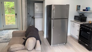 Eine Küche mit einem Edelstahl-Kühlschrank, einer Mikrowelle und einem Herd. Ein beiges Sofa mit Decke.
