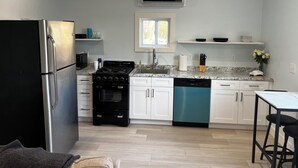 Eine moderne Küche mit Kühlschrank, Herd, Backofen, Geschirrspüler und einem Fenster über der Spüle.