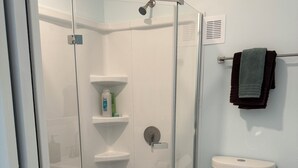 Ein modernes Badezimmer mit einer gläsernen Duschkabine, einer Toilette und einem Waschbecken.