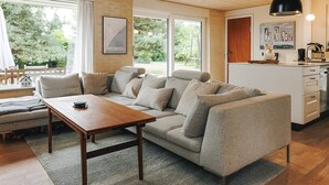 Een moderne woonkamer met een bank, een houten salontafel en een keuken met een spoelbak en kasten.