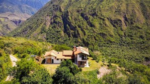 A two-story house with a sloped roof, surrounded by lush greenery and mountains. - TCFR - Stay in a UNESCO Biosphere Reserve - Nature, Comfort, and Adventure! (Quito)