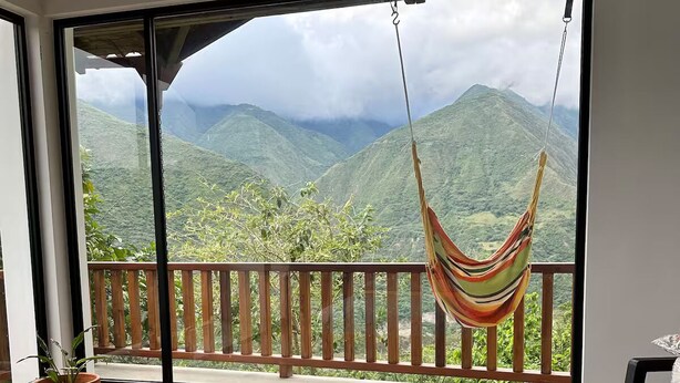 A bedroom with a large window, a hammock, a bed, and a potted plant. - TCFR - Stay in a UNESCO Biosphere Reserve - Nature, Comfort, and Adventure! (Quito)