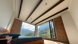 A modern room with a large window, a wooden bench, and a view of mountains. - TCFR - Stay in a UNESCO Biosphere Reserve - Nature, Comfort, and Adventure! (Quito)