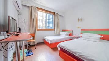A hotel room with two beds, a desk with a chair, a television, and a window with curtains.