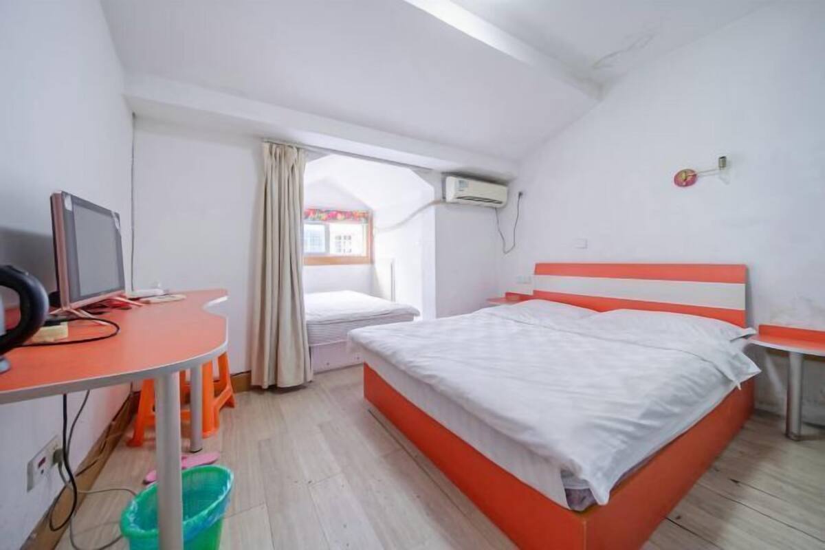 A bedroom with a bed, a desk, a chair, and a window.