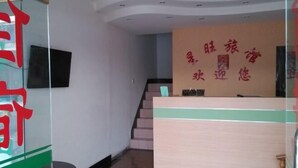 Een receptiegedeelte met een houten receptiebalie, een trap en een muur met Chinese karakters.
