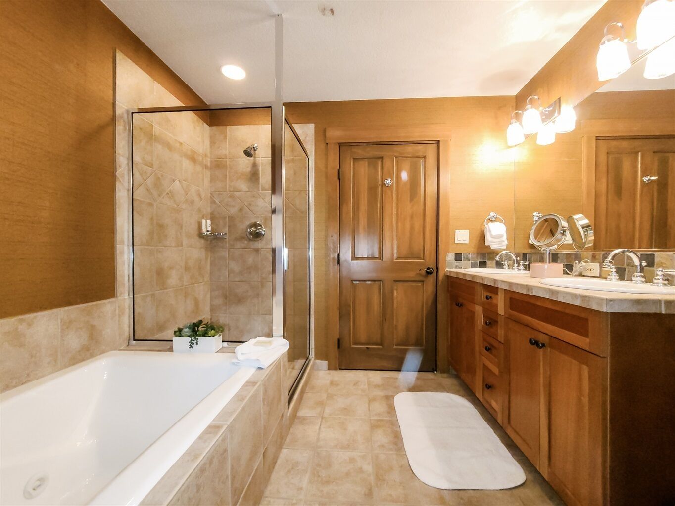 Un baño moderno con ducha envuelta en vidrio, una bañera y un tocador con espejo y lavabo.