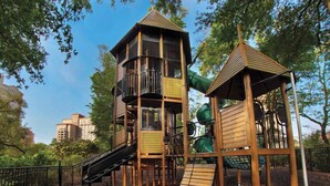 Une aire de jeux avec un toboggan en bois, une structure d’escalade et une tour d’observation.