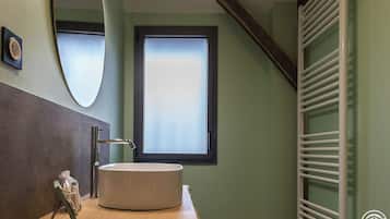 Un baño con un lavabo redondo, un espejo y una ventana.