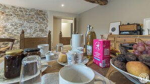 Un comedor rústico con paredes de piedra, vigas de madera y diversos alimentos sobre la mesa.