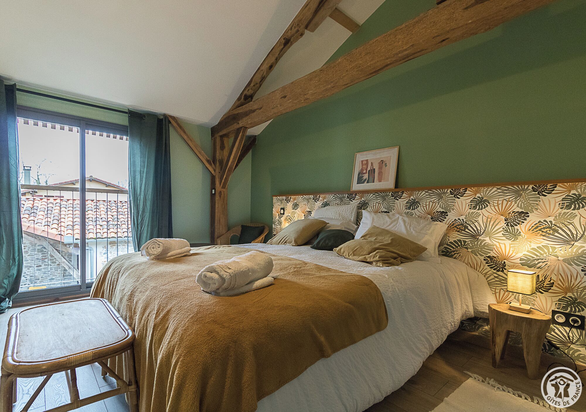A bedroom with a bed, a nightstand, a chair, and a window with curtains.