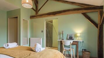A bedroom with a bed, a desk, and a chair. There is a radiator, a window, and a door.