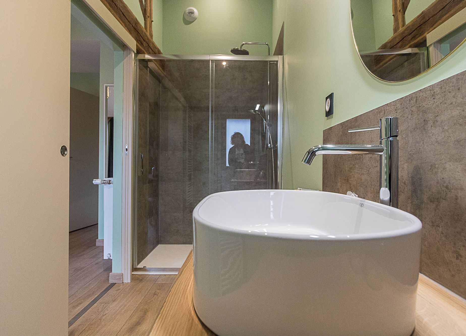 A modern bathroom with a freestanding bathtub, a glass shower enclosure, and a wooden vanity.