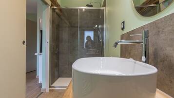 A modern bathroom with a freestanding bathtub, a glass shower enclosure, and a wooden vanity.