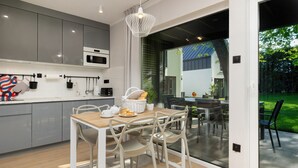 A modern kitchen with grey cabinets, a wooden dining table, and a chandelier. - Ferienhaus in Meernahe, Trzesacz (Rewal)