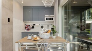 A modern kitchen with grey cabinets, a wooden dining table, and white chairs. - Ferienhaus in Meernahe, Trzesacz (Rewal)