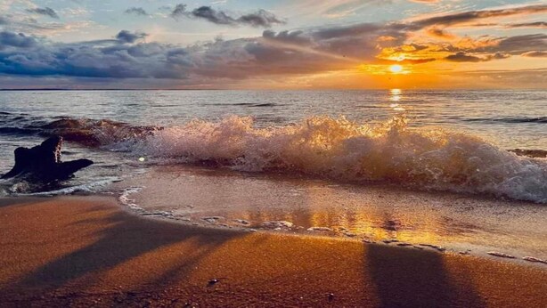 A beach scene with waves crashing onto the shore and a sunset in the background. - Ferienhaus in Meernahe, Trzesacz (Rewal)