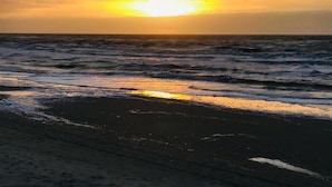 Een strand met golven en een zonsondergang.