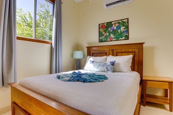 A neatly made bed with a blue towel, a wooden headboard, and a nightstand with a lamp.