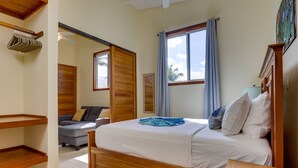 Un dormitorio con cama de madera, un sofá, una ventana con cortinas y un ventilador de techo.