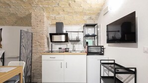 A compact kitchen with white cabinets, a microwave, a stove, and a small refrigerator. - Paradise Vatican Home (Roma)