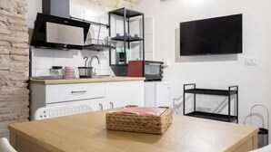 A compact kitchen with a microwave, shelves, and a TV. - Paradise Vatican Home (Roma)
