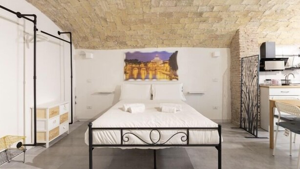 A bedroom with a bed, a desk, and a chair. There is a painting on the wall and a window with a view of a building. - Paradise Vatican Home (Roma)