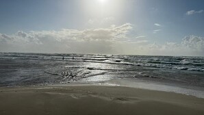 A beach with waves, a clear sky, and the sun shining. - 6 Person Holiday Home in Blokhus (Blokhus)