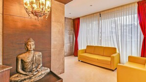 Ein Zimmer mit einer Buddha-Statue, einem gelben Sofa und einer Kristallleuchtre.
