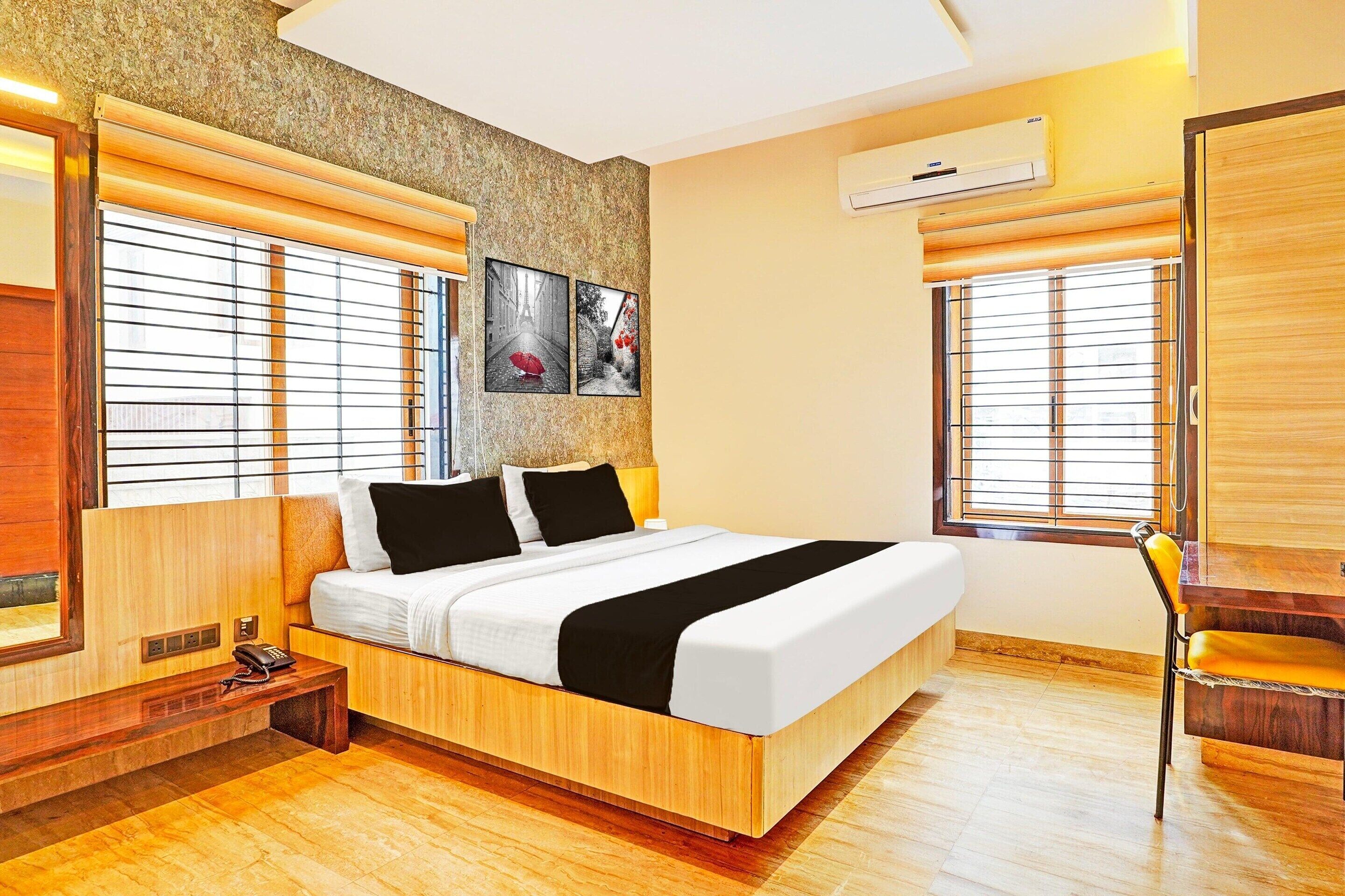 Une chambre d’hôtel moderne dotée d’un grand lit, d’un parquet et de deux fenêtres équipées de stores.