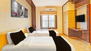 Ein Hotelzimmer mit zwei Betten, einem Fernseher, einer Klimaanlage und einem Fenster mit Jalousien.