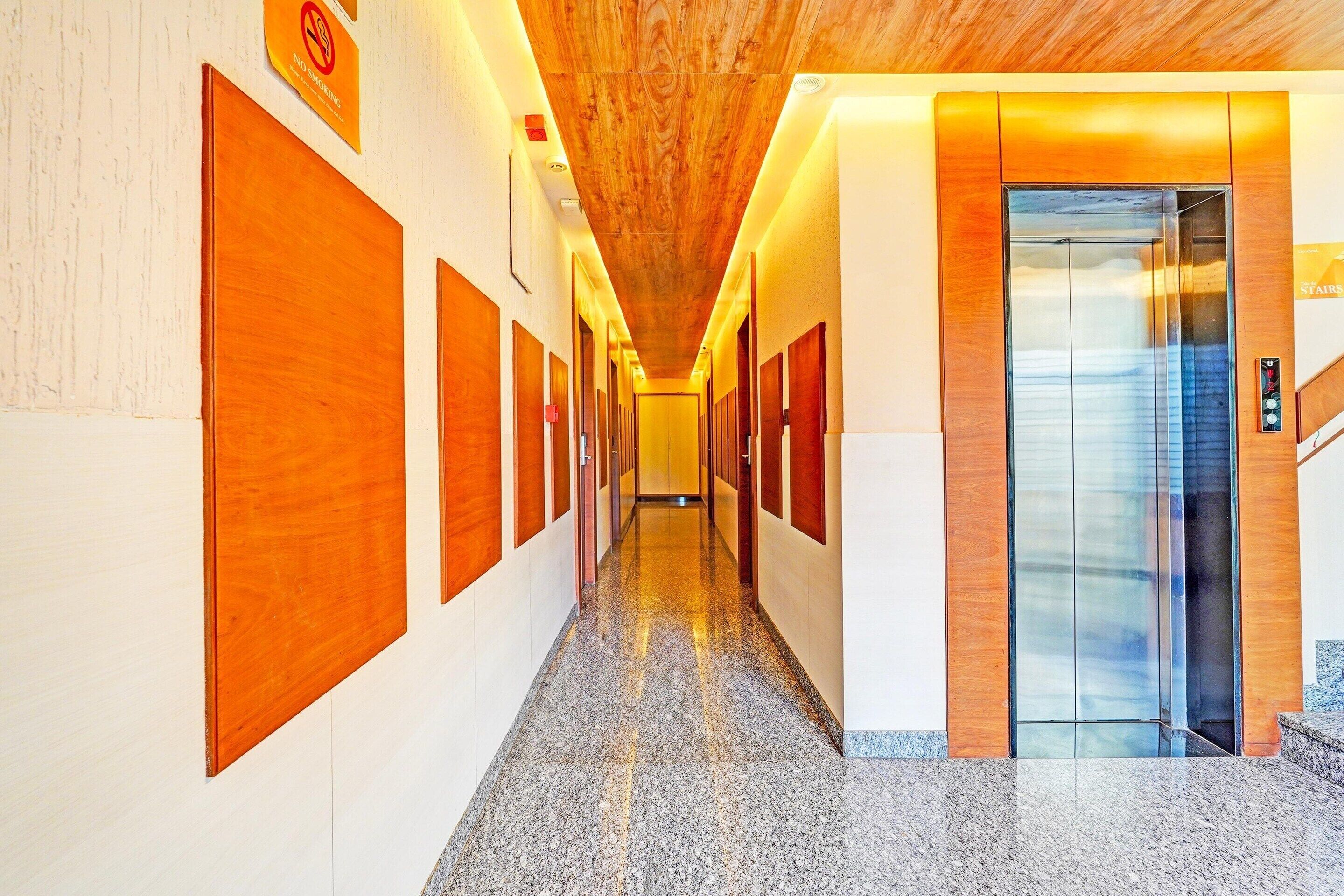 A hallway with wooden doors, a glass elevator, and a sign indicating no smoking.