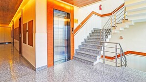 Ein modernes Interieur mit einer Marmortreppe, einem Aufzug und einer Holzzieldecke.