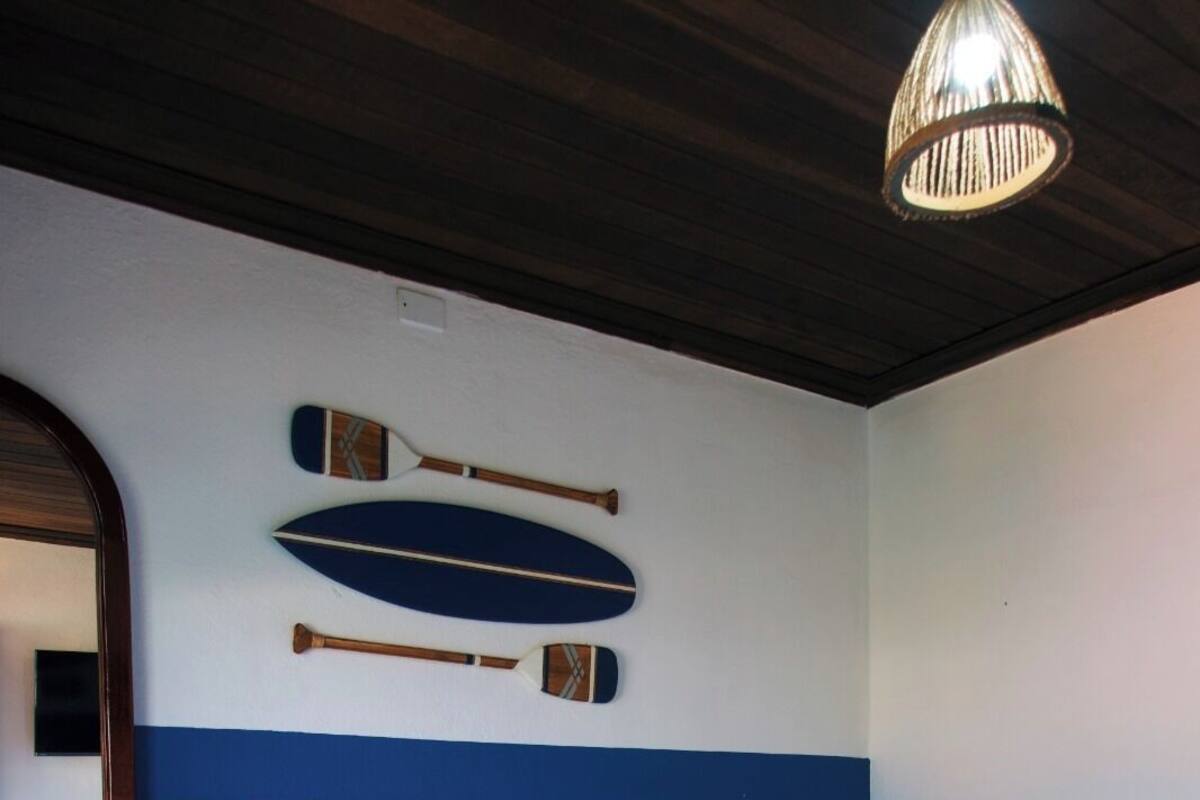 Una cama bien hecha con cabecera de madera, un espejo montado en la pared y una lámpara en el techo.