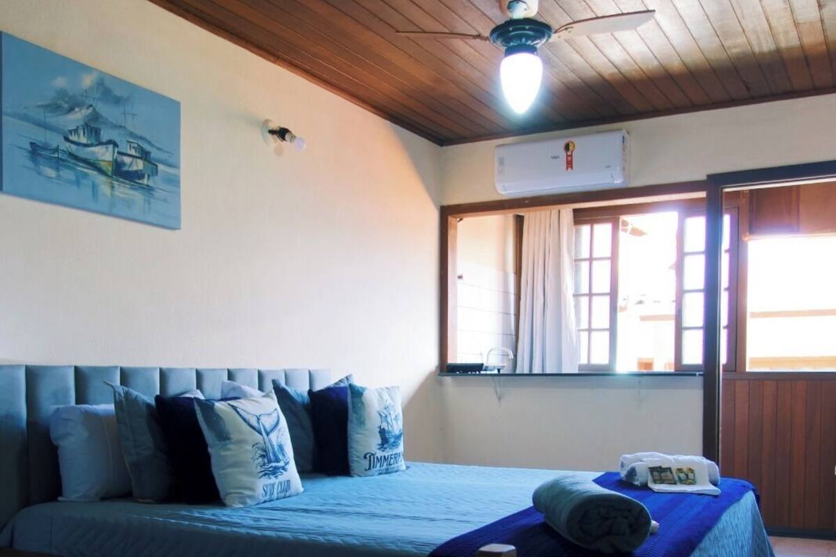 Una habitación con dos camas, ventilador de techo, aire acondicionado y una ventana con cortinas.