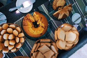 Una mesa con diversos alimentos, incluyendo pan, bollos y un pastel.