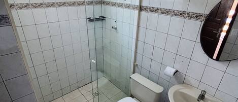A bathroom with a toilet, sink, and glass-enclosed shower.