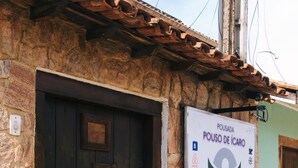 A stone building with a wooden door and a signboard advertising a business. - Pousada Pouso de ícaro (Paraty)
