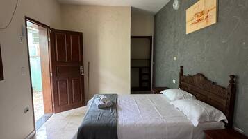 Un dormitorio con dos camas, un ventilador de techo, un cuadro en la pared y una puerta que da a otra habitación.