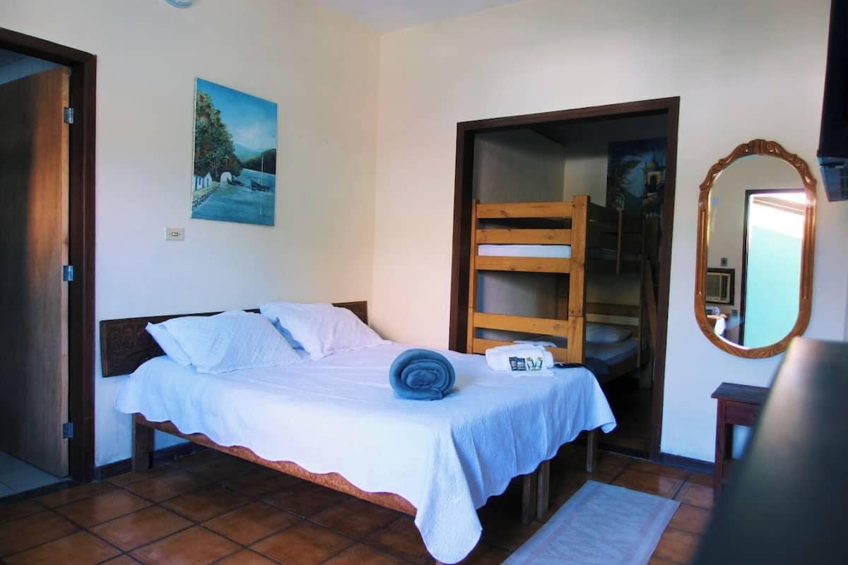 Un dormitorio con una cama, una escalera de madera, un espejo y un cuadro en la pared.