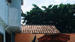 A swimming pool with lounge chairs and umbrellas, surrounded by a building with a tiled roof and a white exterior. - Pousada Pouso de ícaro (Paraty)