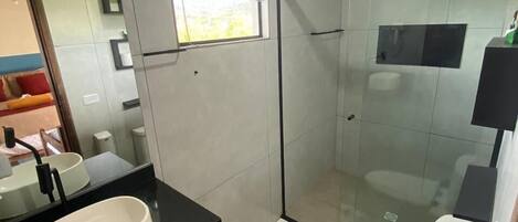 Ein modernes Badezimmer mit Duschkabine aus Glas, Waschbecken, Toilette und einem kleinen Mülleimer.