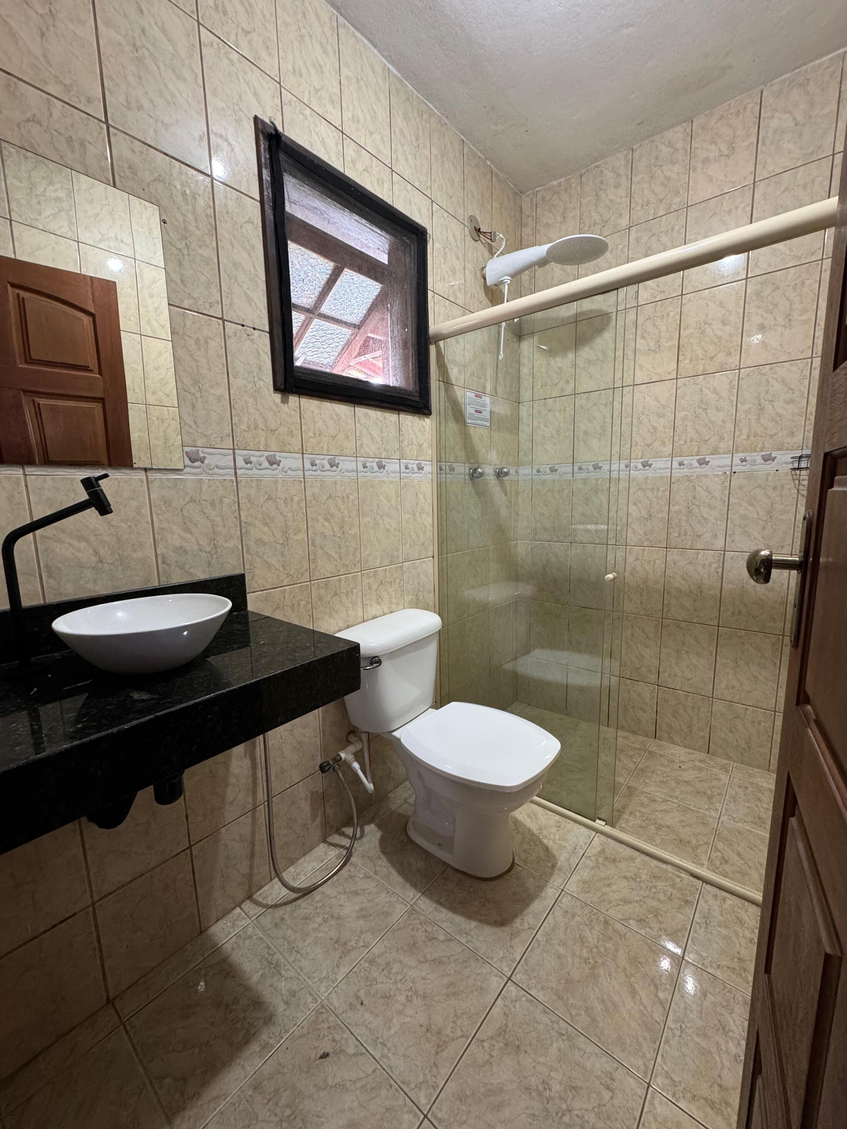 Un baño con inodoro, lavabo y ducha con mampara de vidrio.