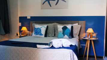 A hotel room with a bed, two bedside tables with lamps, a starfish artwork on the wall, and a blue accent wall.