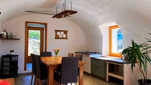 A cozy kitchen with a dining area, featuring a wooden table, chairs, and a red sofa. - Detached house on three levels with garden, a stone's throw from the center of Teglio (Teglio)