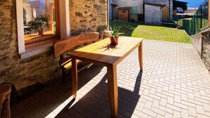 A wooden interior with a table and bench, a window with plants, and a view of a mountain landscape. - Detached house on three levels with garden, a stone's throw from the center of Teglio (Teglio)