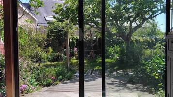 Une terrasse en bois donnant sur le jardin, une porte en métal et un meuble blanc.